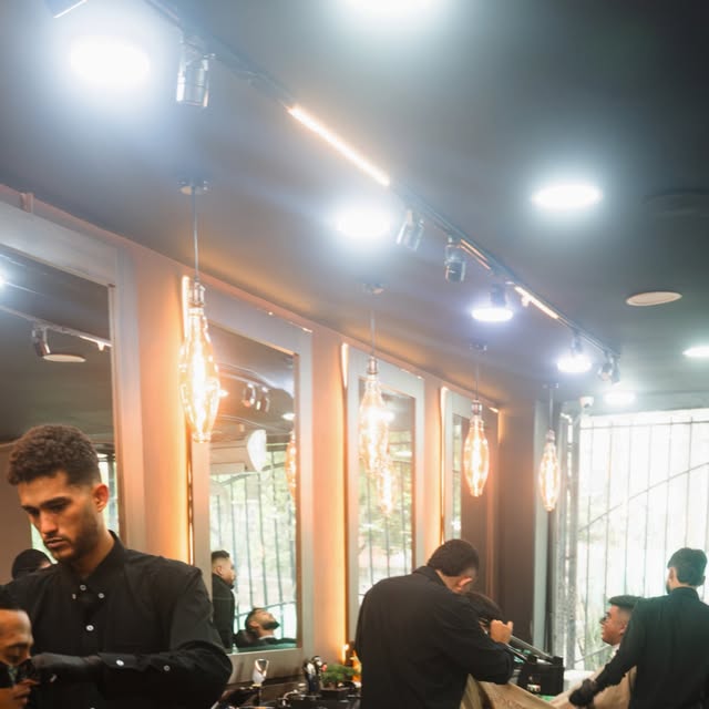 El salón con bombillos y barberos trabajando
