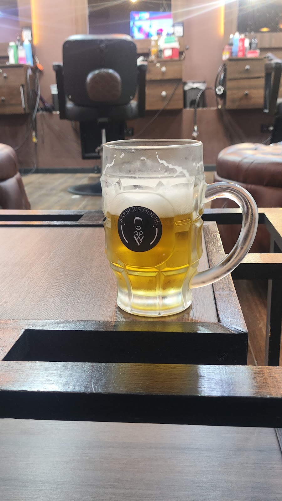 Una jarra de cerveza con el logo de Barber's House, frente a las sillas