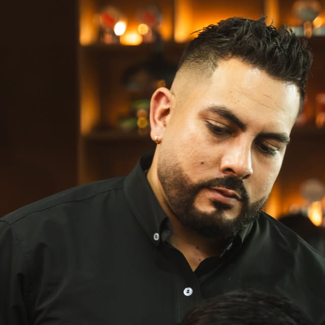 Un barbero de camisa negra, concentrado en el corte