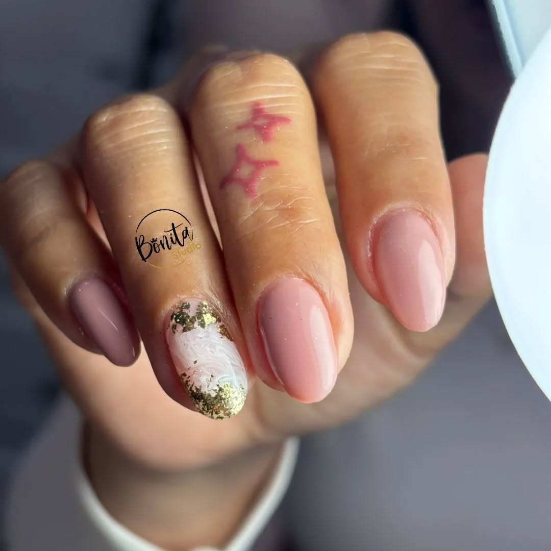 Uñas almendradas nude y malva, una con mármol blanco y hojilla dorada