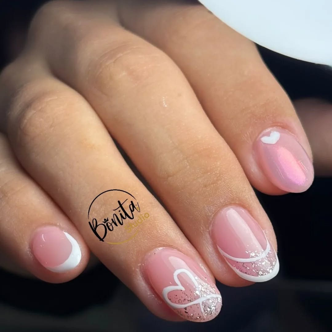 Uñas cortas rosadas con corazones blancos, francés y brillo plateado