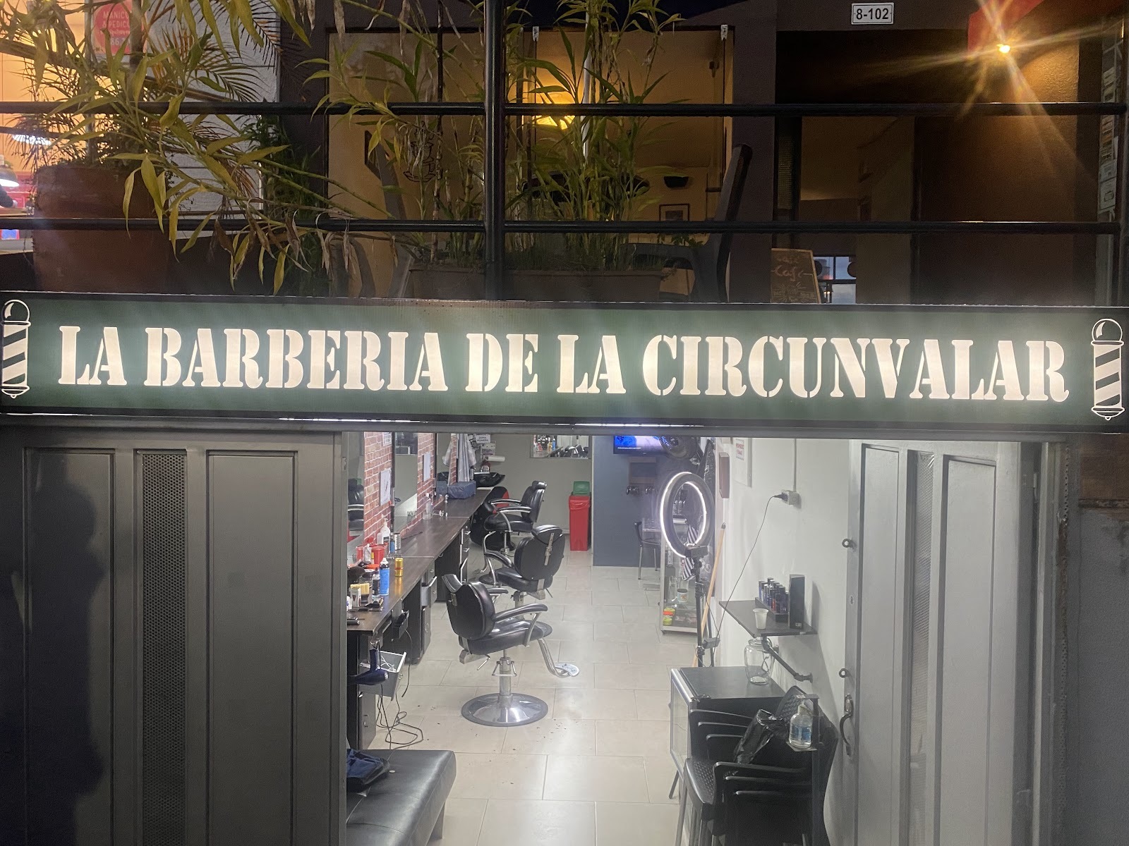 Aviso iluminado de La Barbería de la Circunvalar sobre la entrada abierta, de noche