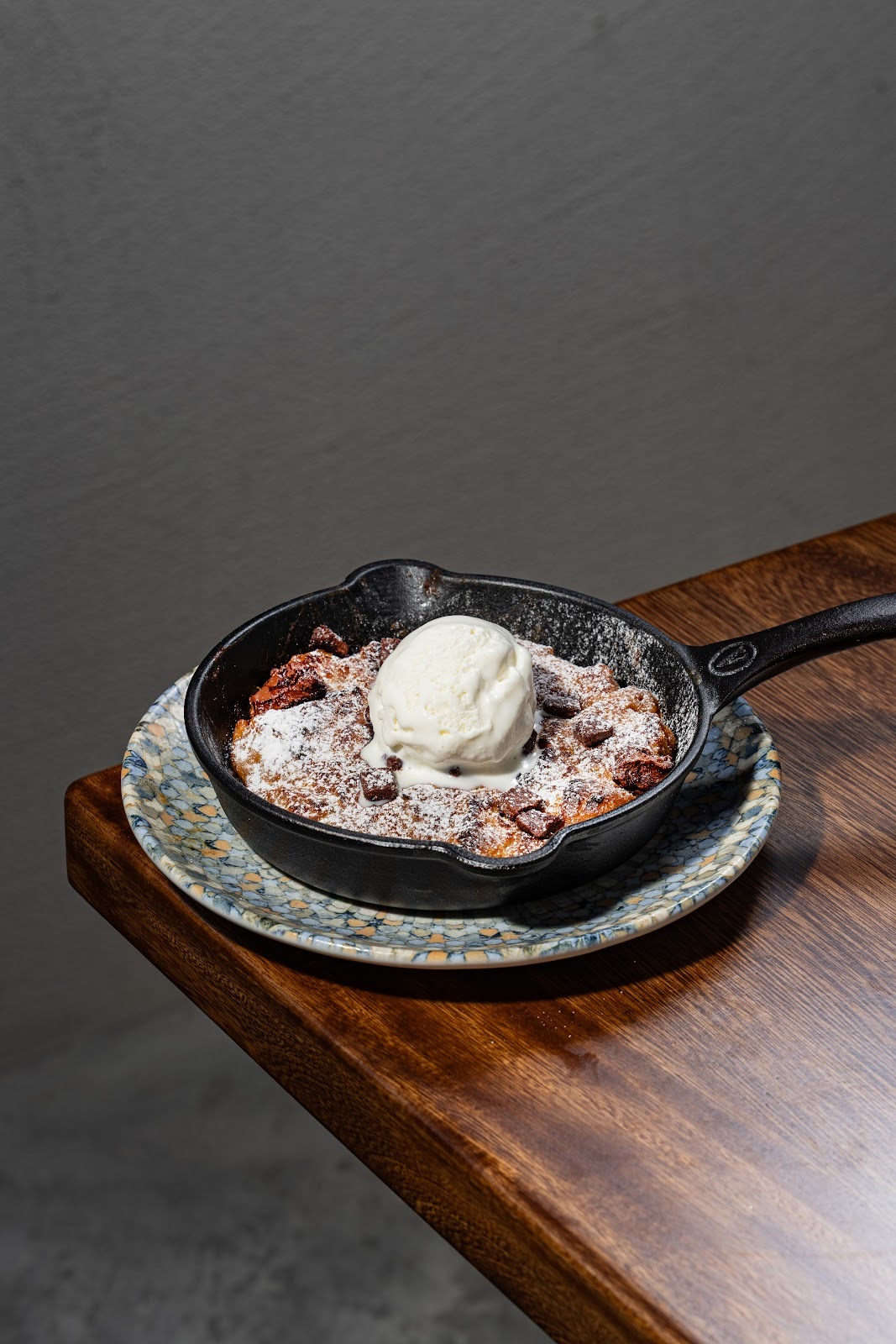 Postre en sartén de hierro con helado y azúcar en polvo sobre madera